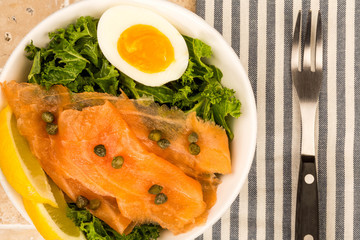 Bowl Of Smoked Salmon With Capers And Kale With A Boiled Egg And Lemon