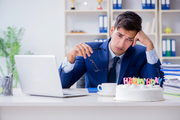 Young businessman celebrating birthday alone in office