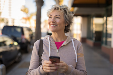 Mature caucasian woman walking texting cell phone