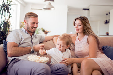 Obraz premium Cute son and his parents eating popcorn