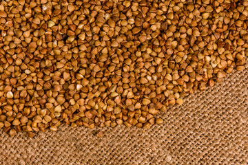 Pile of the raw buckwheat on sackcloth. Top view