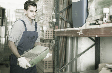 young male in uniform is choosing cement in the building store