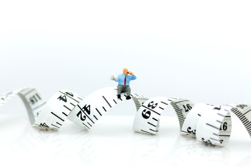 Miniature people: Man sitting on the waistline and drinking coffee. Image use for health concept, take care yourself, exercise.