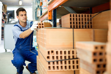 Shop assistant man is checking quality of bricks