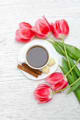 Fototapeta na wymiar Mug of coffee and pink tulips, light wooden background.