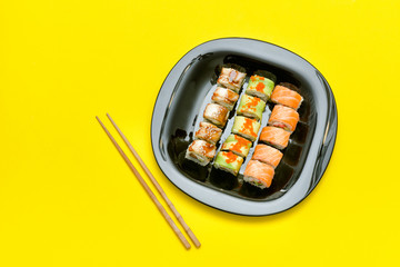 Black plate with various rolls on a yellow background. Top view