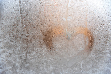Valentines day concept heart shape written on a frosty window and a frosty glass.