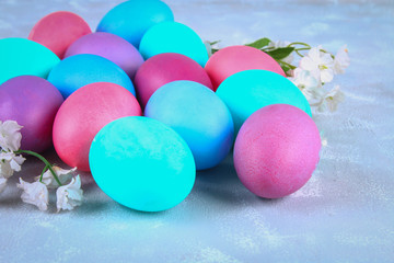 Colored Easter eggs with white flowers on a gray concrete background.