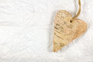 Wooden heart on white handmade crumple paper. Love concept.