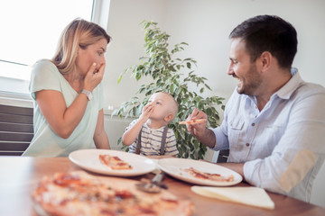 Family eat pizza in kitchen.