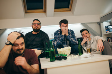 Group of friends watching sport on TV at home