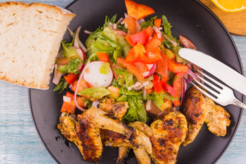 Fried chicken wings in rustic style with salad and bread