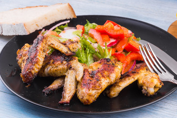 Fried chicken wings in rustic style with salad and bread