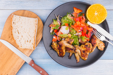 Fried chicken wings in rustic style with salad and bread