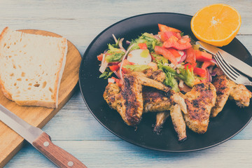 Fried chicken wings in rustic style with salad and bread