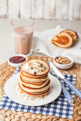 Pancakes stack on a white plate with cream and granola. Maslenitsa. Traditional Russian holiday