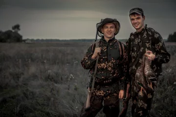 Photo sur Plexiglas Chasser Hommes chasseurs avec trophée dans le domaine rural pendant la période de chasse au crépuscule