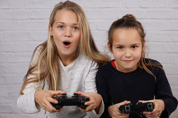 Two sisters kids playing video games at home together. Happy childeren, carefree childhood concept