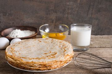 stack of pancakes with butter, milk and ingredients for breakfast.