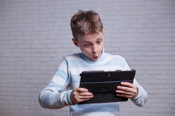 Very surprised teenage boy looking at tablet pc in his hands. Technology, social network, information