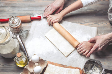 Mother and the daughter cook dough for home-made pastries. Happy family concept. Female and children's hands using rolling pins