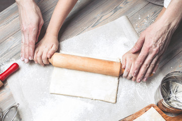 Mother and the daughter cook dough for home-made pastries. Happy family concept. Female and children's hands using rolling pins