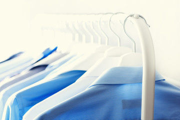 Blue color clothes. Male clothes, jackets and shirts hanging on clothes rail. Copy space. Banner
