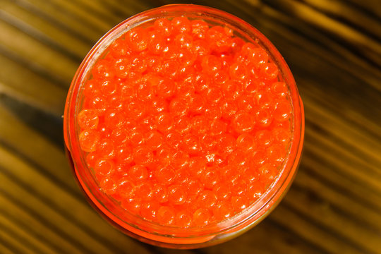 Red caviar in glass jar on wooden table. Top view
