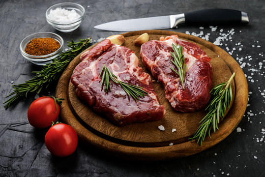 Raw meat with rosemary and spices in a board on black background