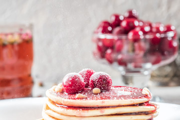 Pancakes homemade cake in stack decorated with berries frozen cherry Sprinkle with sugar powder on white plate