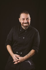 Portrait of a smiling chef looking to the rigth on a black background.