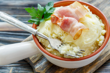 Fork in bowl with mashed potatoes and bacon.