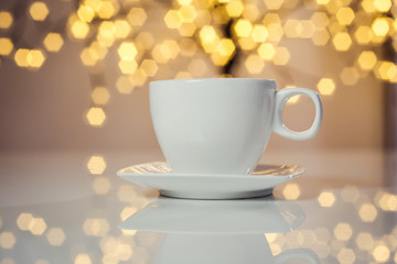Hot tasty coffee cup on the table with background of blurred holiday lights