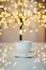 Hot tasty coffee cup on the table with background of blurred holiday lights