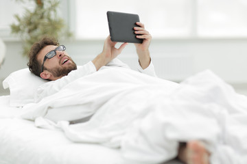 closeup.sleepy man looking at the screen of a digital tablet.