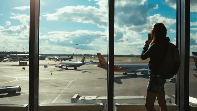 Tursit woman in the airport shoots photos on the smartphone