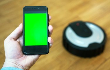 Man using mobile app to control robotic vacuum cleaner. Space for your text. Chroma key.