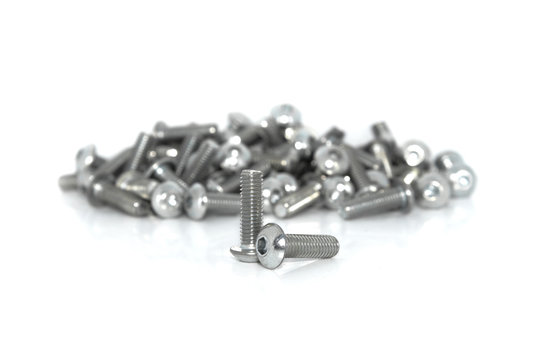 A couple of isolated galvanized industrial steel screws in front of blurt pile on white background
