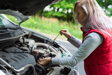 Fototapeta na wymiar Girl checks the oil in the car's engine