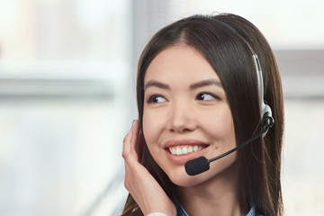 Telemarketing headset asian woman. Young, confident and smiling customer support operator working in office.