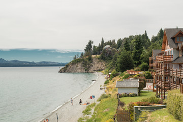 Costa de arena frente al lago, con hoteles y turistas que aprecian la vista