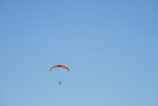 Low angle view of young man motor paragliding against clear blue sky