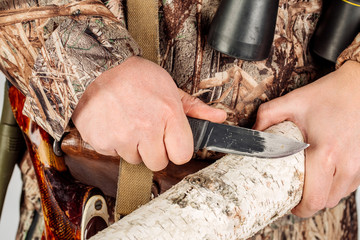 hunter with a knife cut a wooden stick