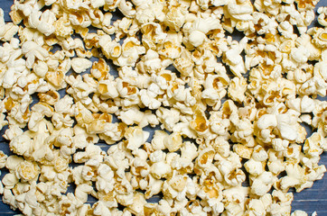 Salted popcorn is scattered on a blue wooden background. The concept of cinema. To watch movie.