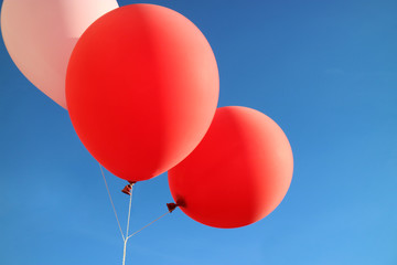 Red and pink balloon against blue sky with copy space