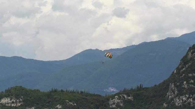 Parasailing Parachute Boating over the beach with alps mountains on the background.