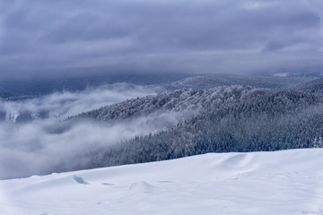 Fototapeta na wymiar Winter foggy mountain landscape. Fairytale evening or afternoon with dramatic clouds in the sky