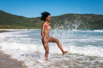 Happy and Playful Beautiful Young Woman in Bikini Playing in Waves at the Beach