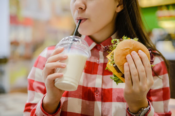 woman eat humburger and drink milk shake