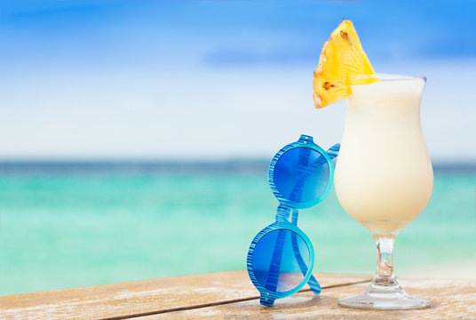 glass of delicious cold pina colada cocktail by the beach